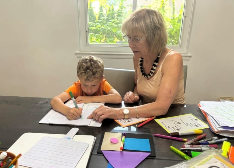 A child practicing letter formation with hands-on guidance
